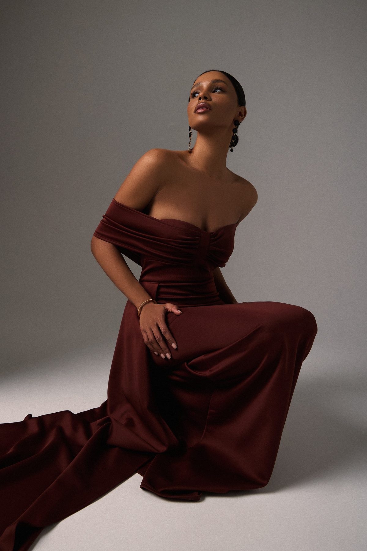 Burgundy satin gown with sculptural draping